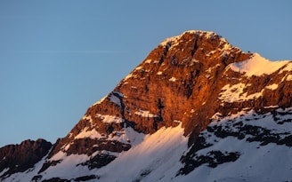 a snow covered mountain with a plane flying in the sky
