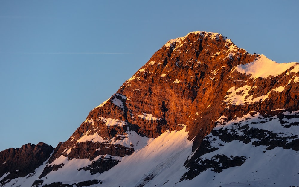 una montagna innevata con un aereo che vola nel cielo