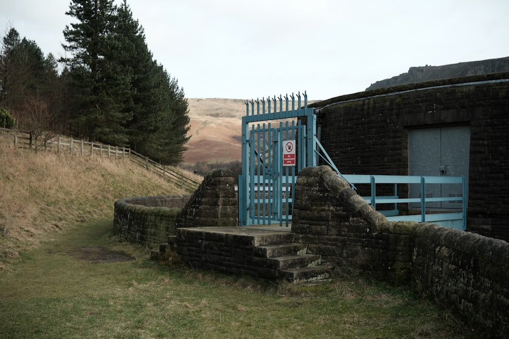 a stone wall with a blue gate and steps