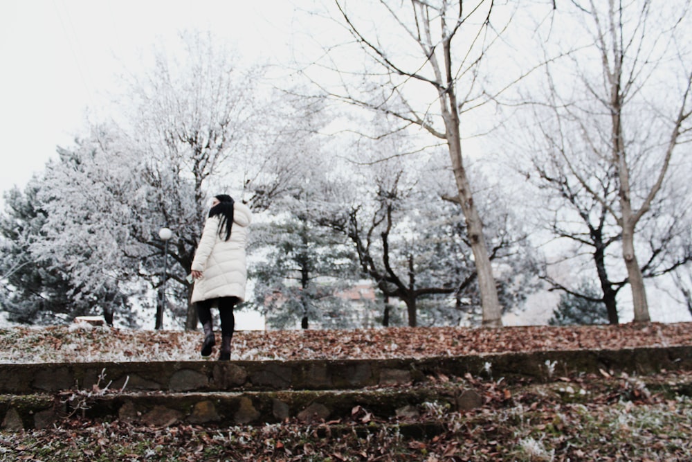 a woman in a white coat is walking in the snow