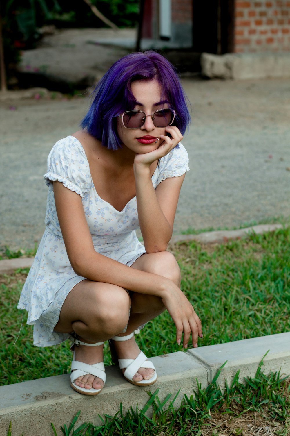 a woman with purple hair sitting on a curb