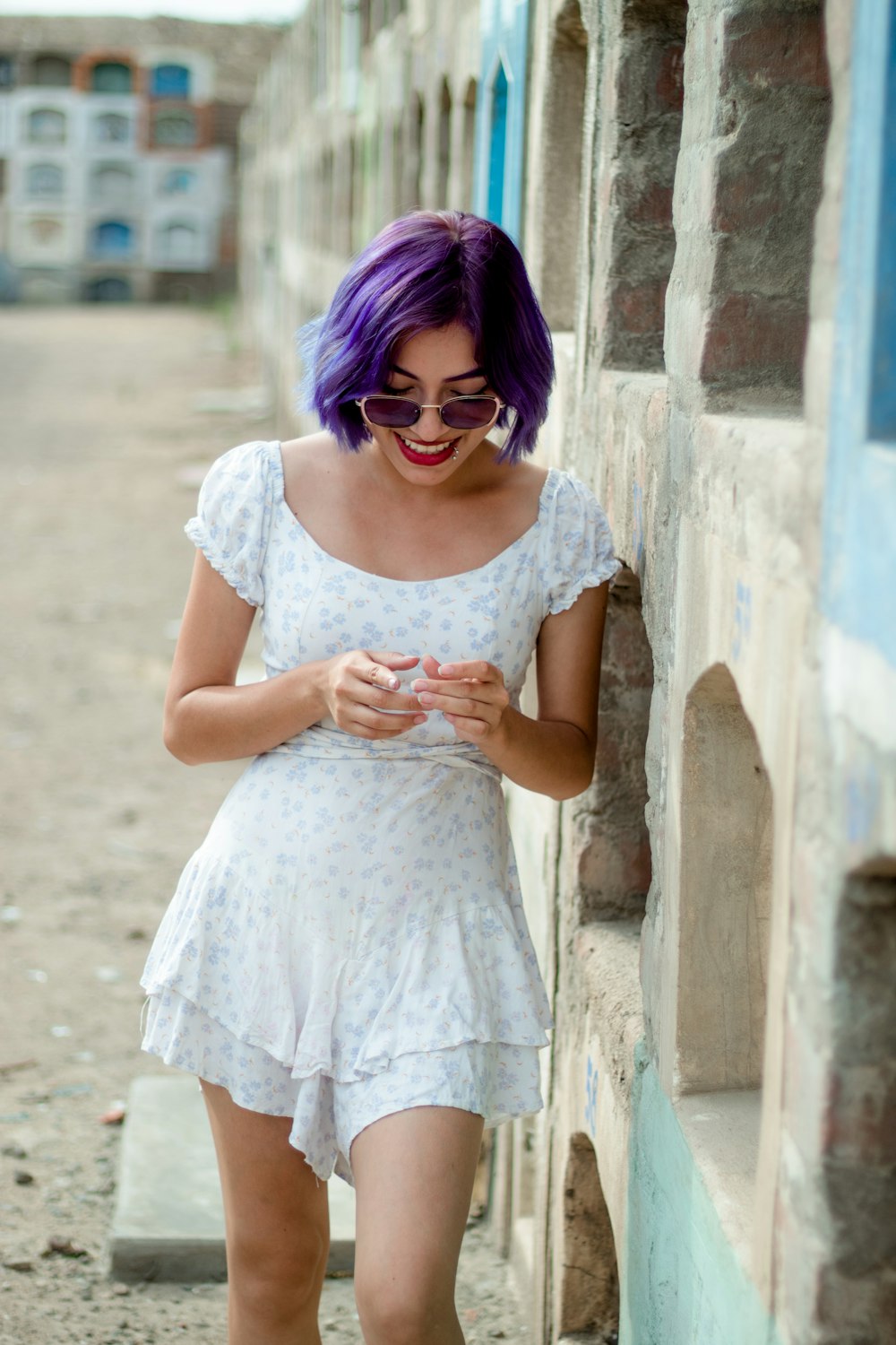 a woman with purple hair is looking at her cell phone