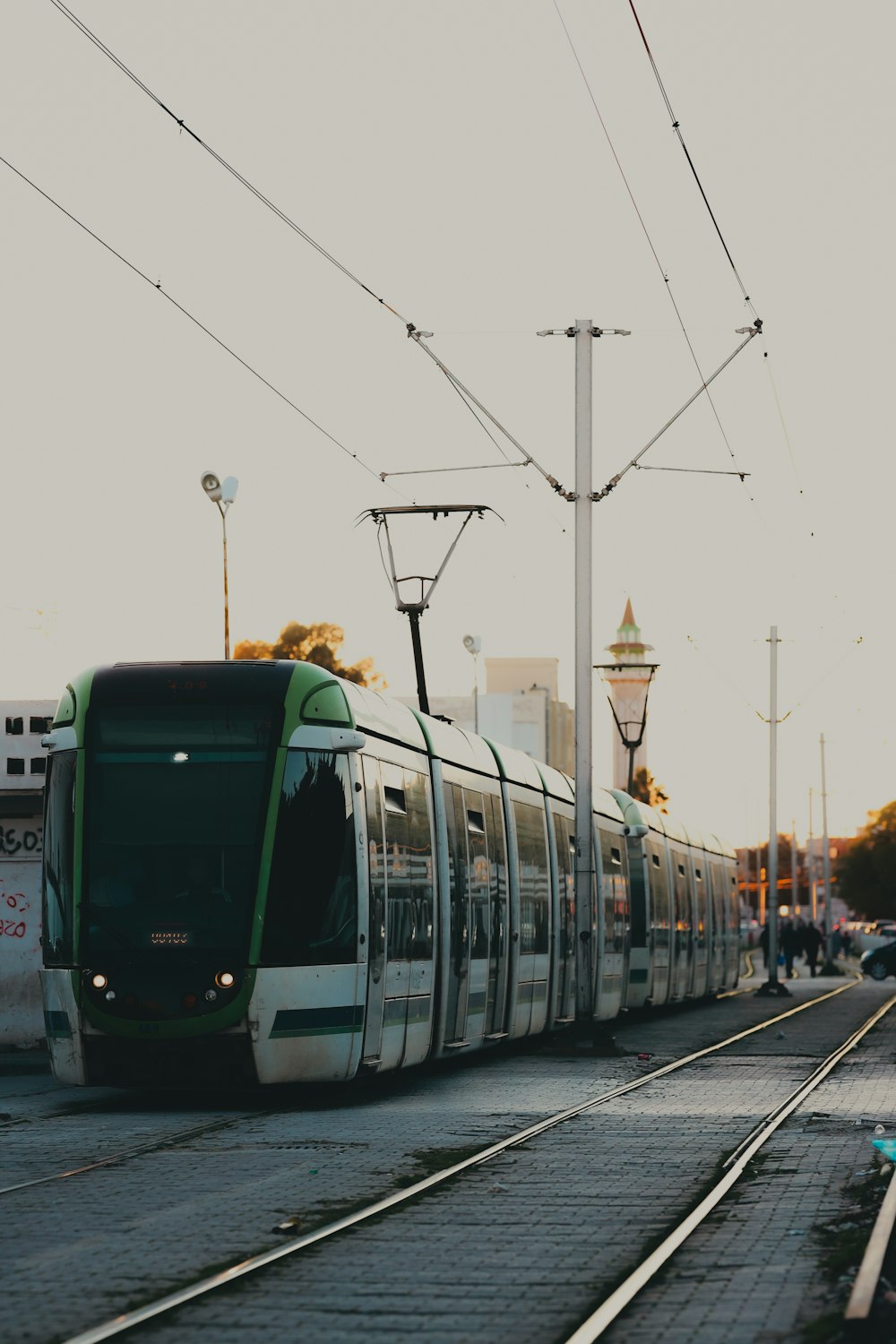 a green and white train traveling down train tracks