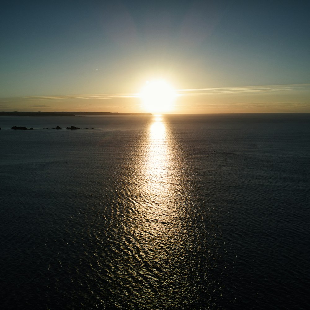 a large body of water with the sun setting in the background