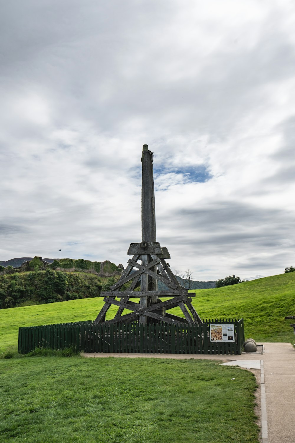 a wooden structure in the middle of a grassy field