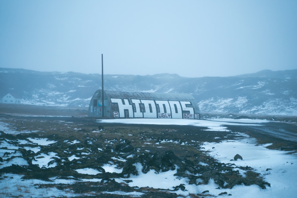 a large sign on a snowy field with mountains in the background