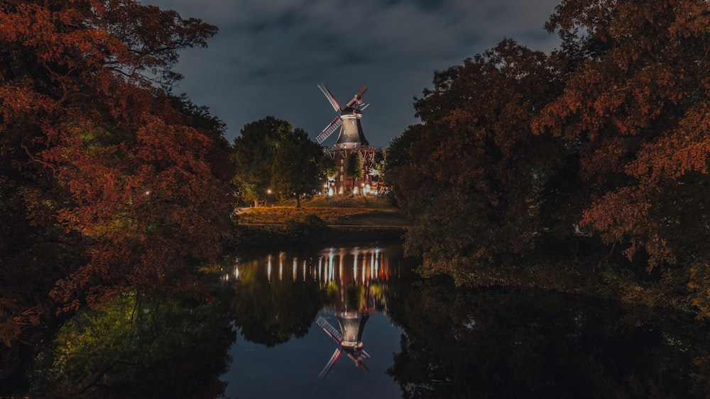 a windmill sitting on top of a hill next to a body of water