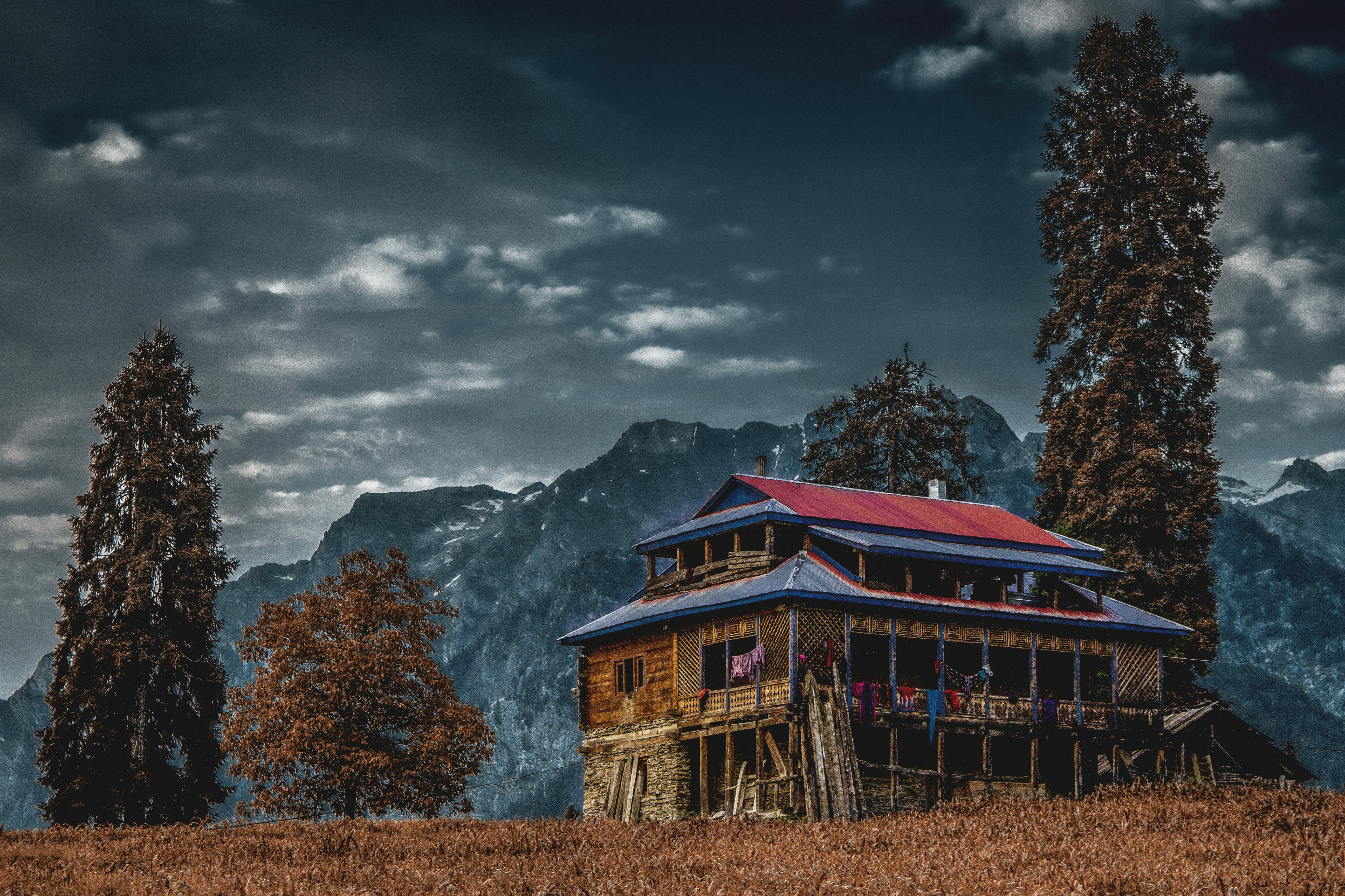 a house in the middle of a field with mountains in the background