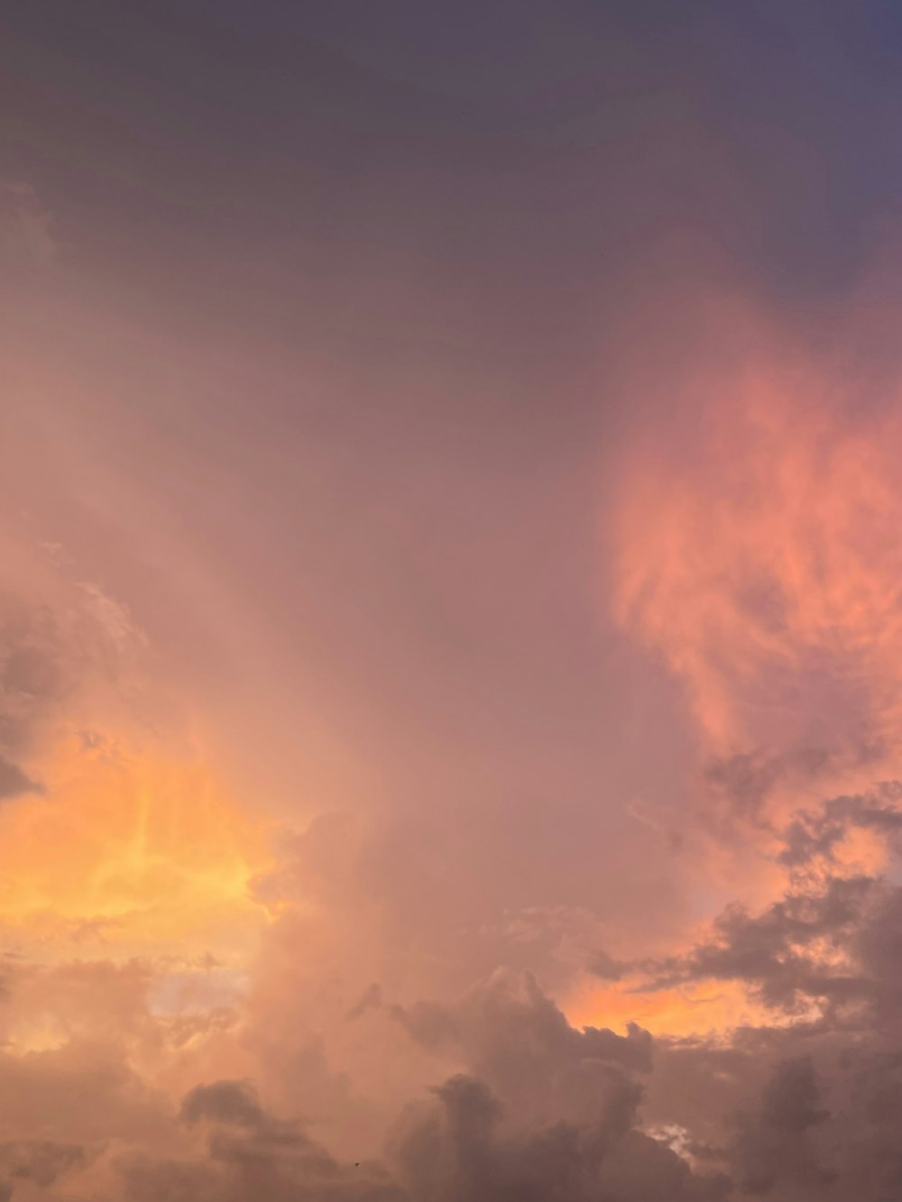 a plane flying through a cloudy sky at sunset