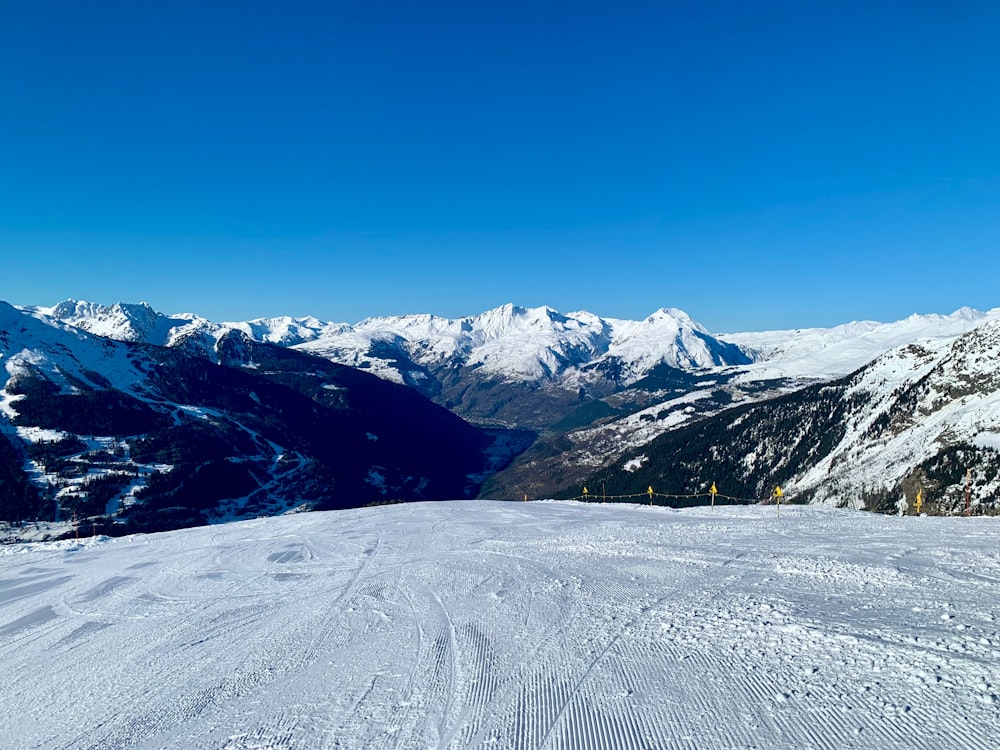 una persona con esquís de pie en la cima de una ladera cubierta de nieve