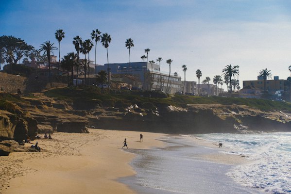 A couple of people walking along a beach next to the ocean — San Diego, United States