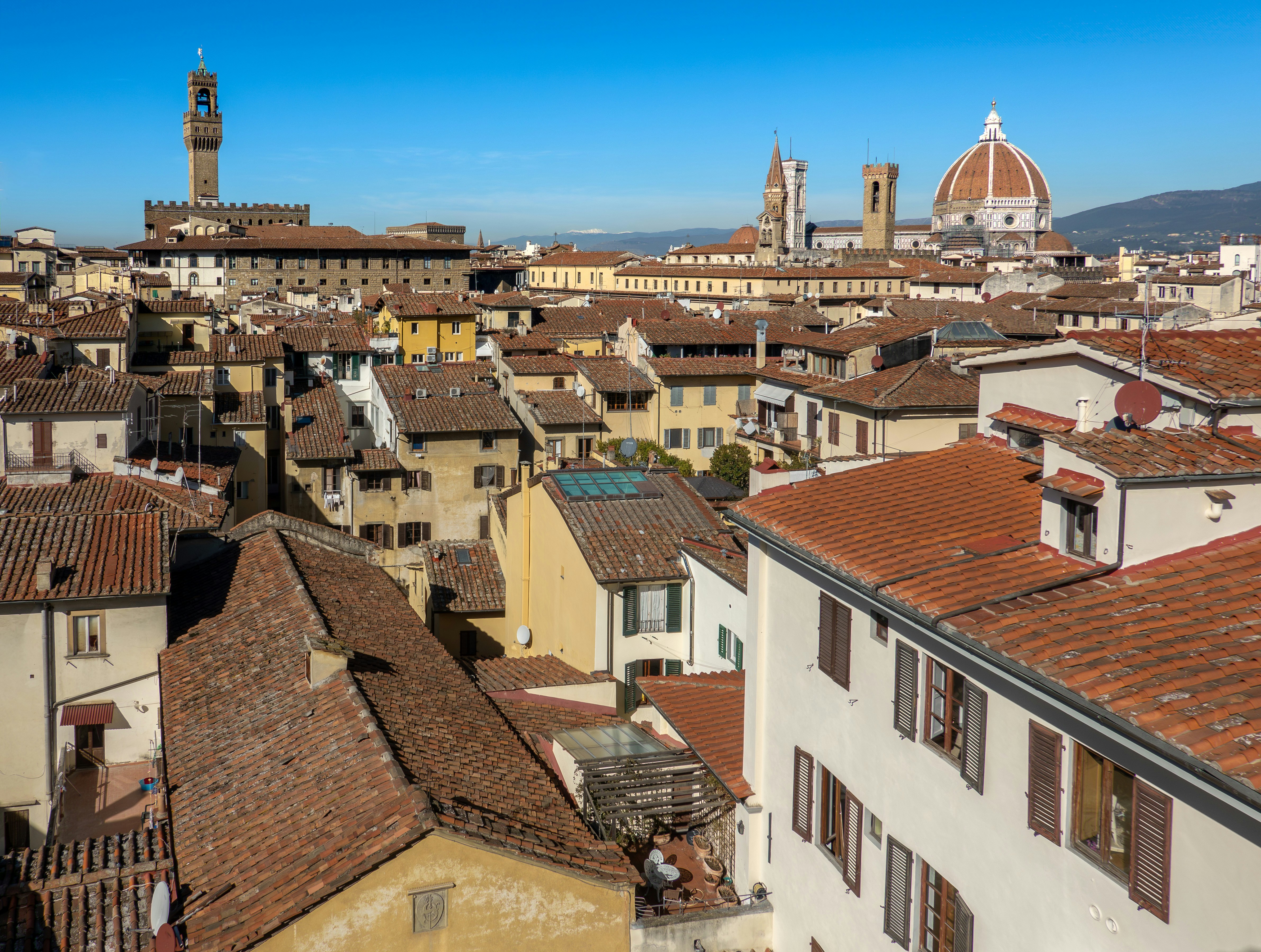 a view of a city from a high point of view, Rooftops of Florence with iconic Duomo and Palazzo Vecchio in the distance