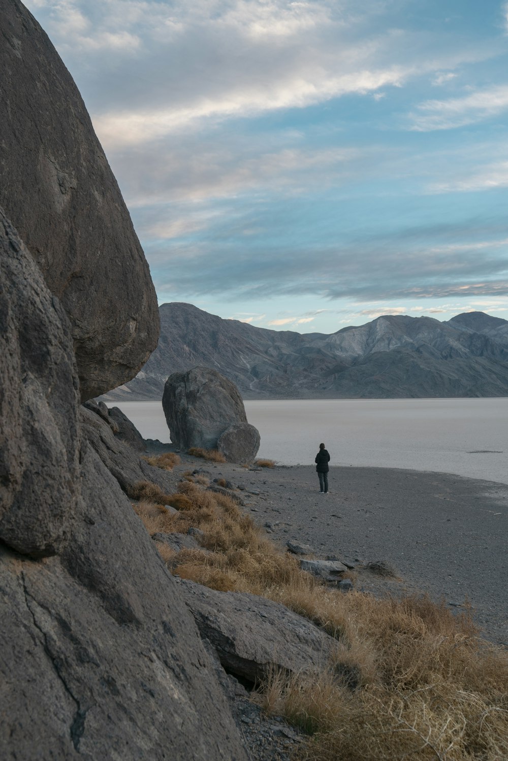 a person standing on a beach next to a large rock