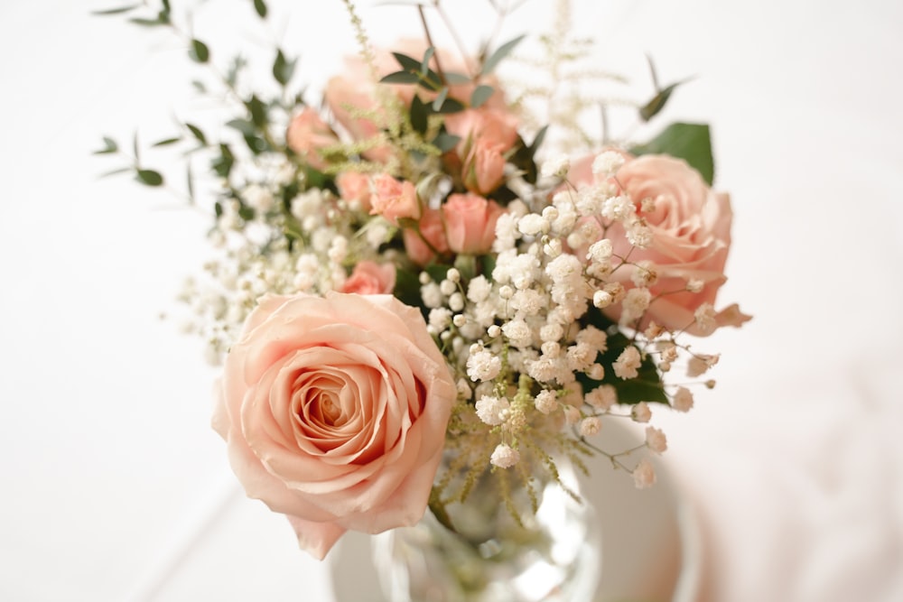 a vase filled with pink roses and baby's breath