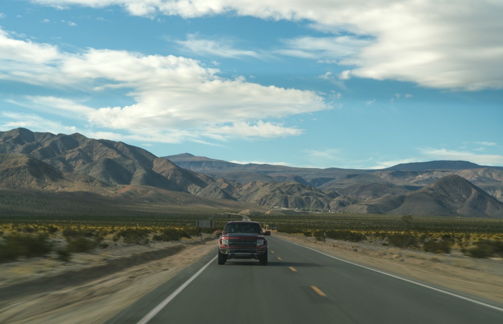 a truck driving down a highway with mountains in the background