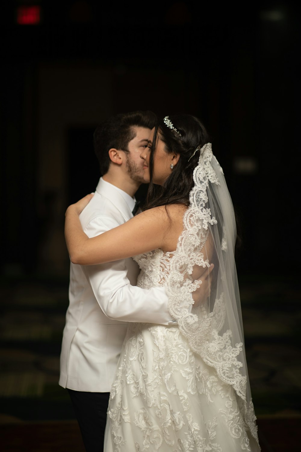 a bride and groom kissing in the dark