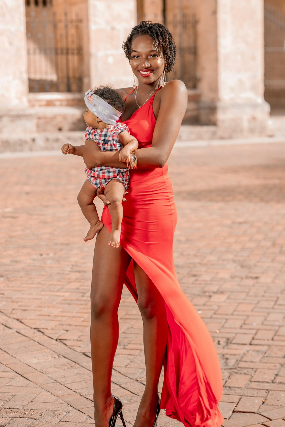 a woman in a red dress holding a baby