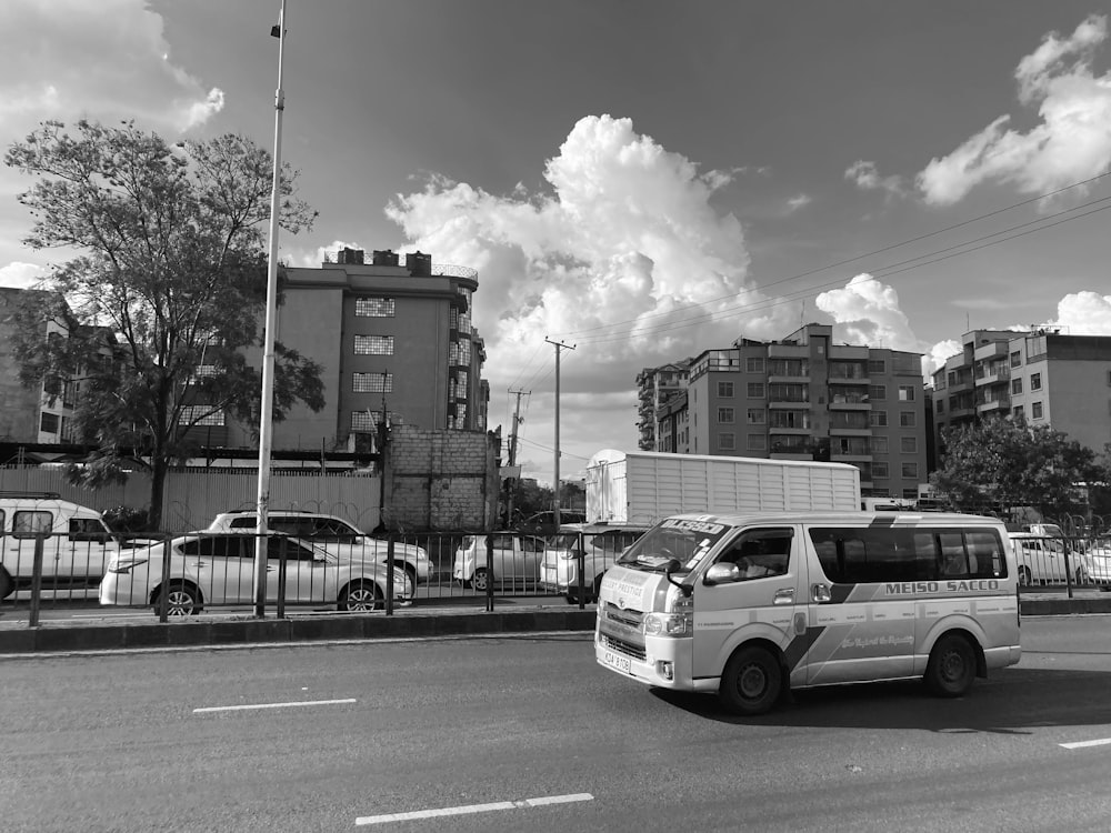 a white van driving down a street next to tall buildings