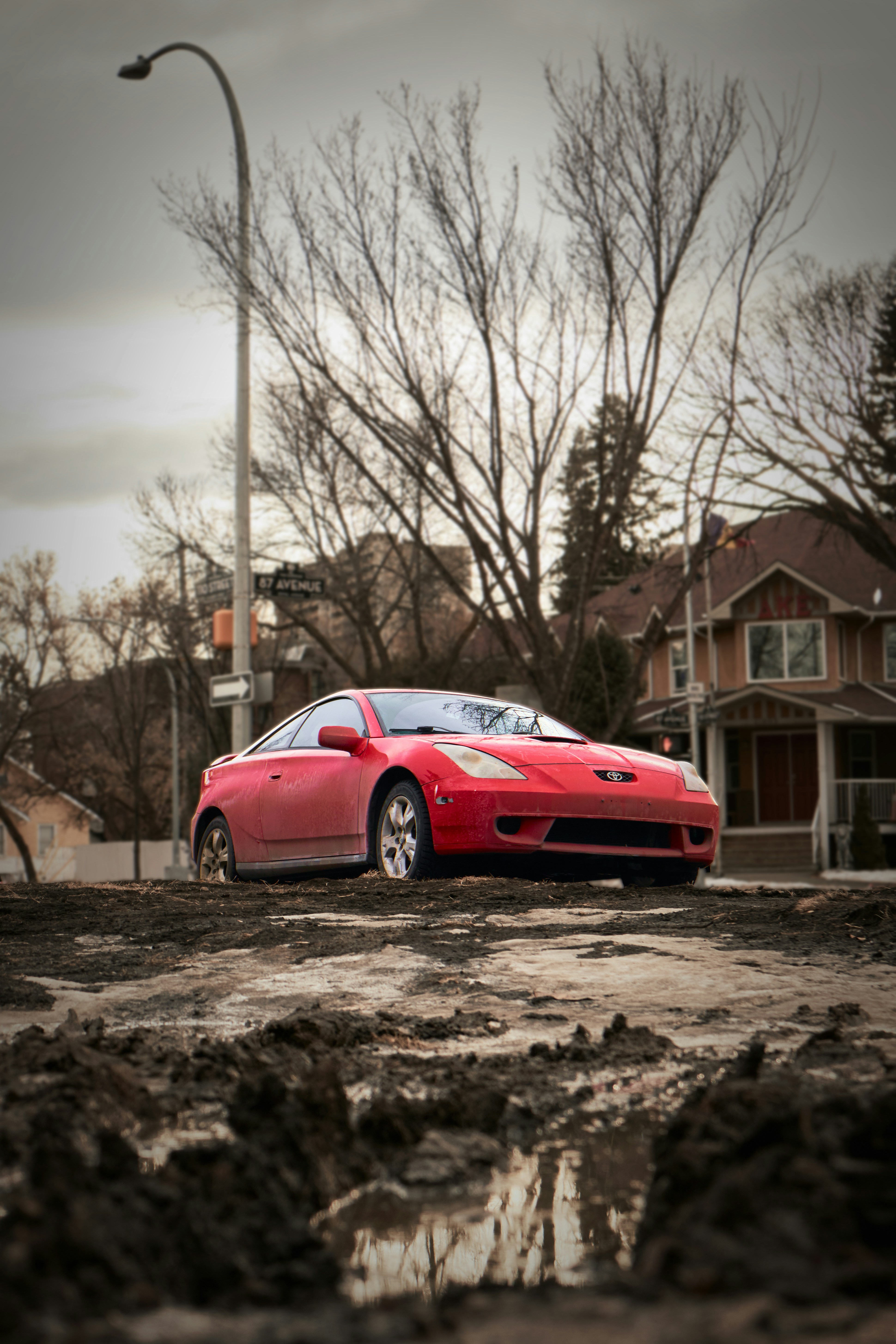 a red sports car parked in a muddy lot