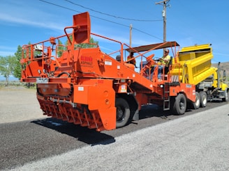 a large orange truck with a yellow dump truck behind it