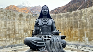 a statue of a woman sitting on top of a rock