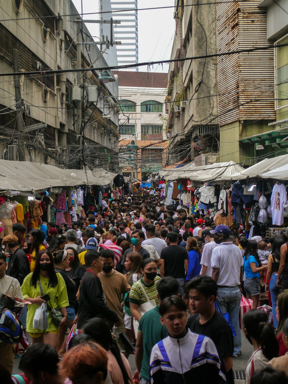 a crowd of people walking down a street next to tall buildings