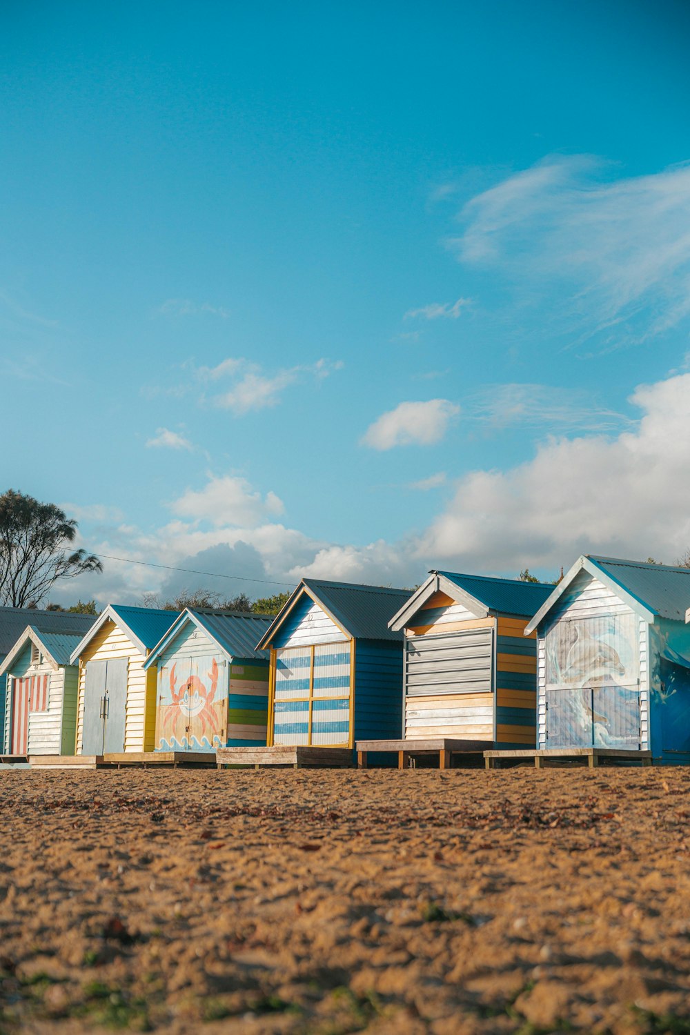 a row of beach huts sitting on top of a sandy beach