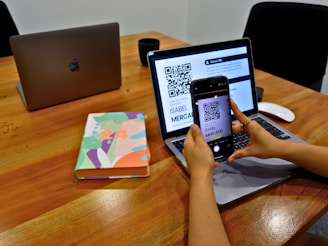 a person sitting at a table with a laptop and a cell phone
