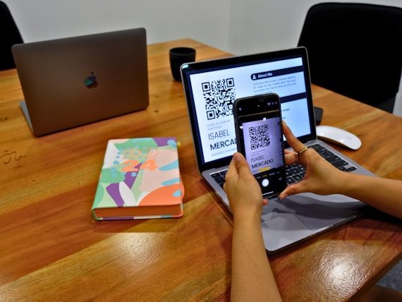 a person sitting at a table with a laptop and a cell phone