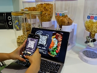 a person using a cell phone and a laptop on a table