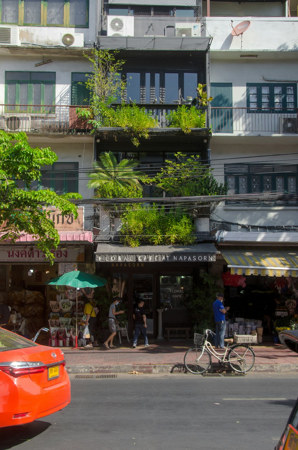 a red car driving down a street next to a tall building