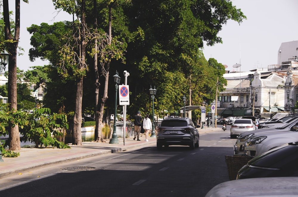 a city street lined with parked cars and trees