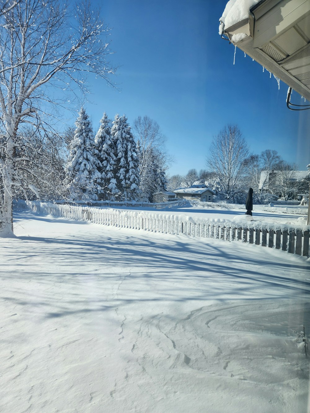 a snow covered yard with a fence and trees