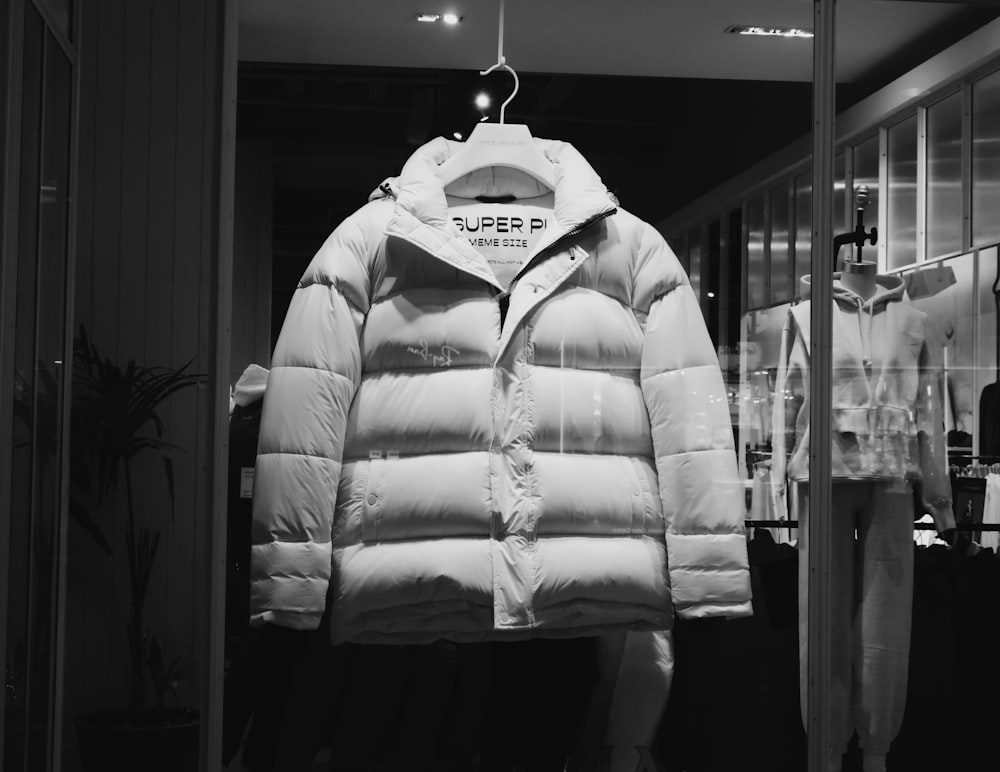 a white puffer jacket hanging in a store window