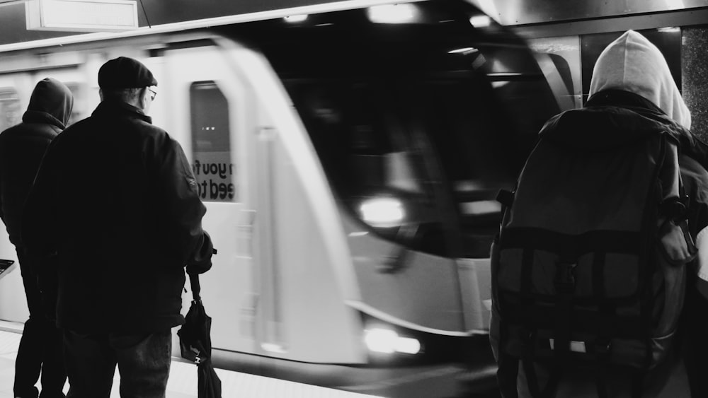 a black and white photo of people waiting for a train