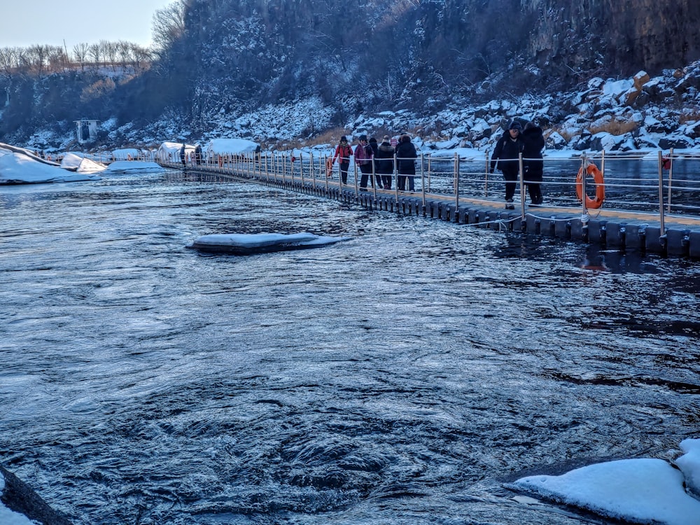 a group of people standing on a bridge over a river