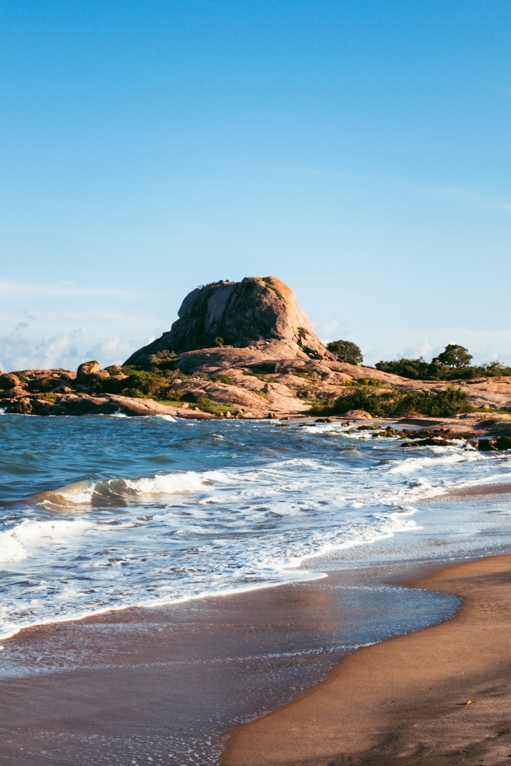 a rocky outcropping on a beach next to the ocean