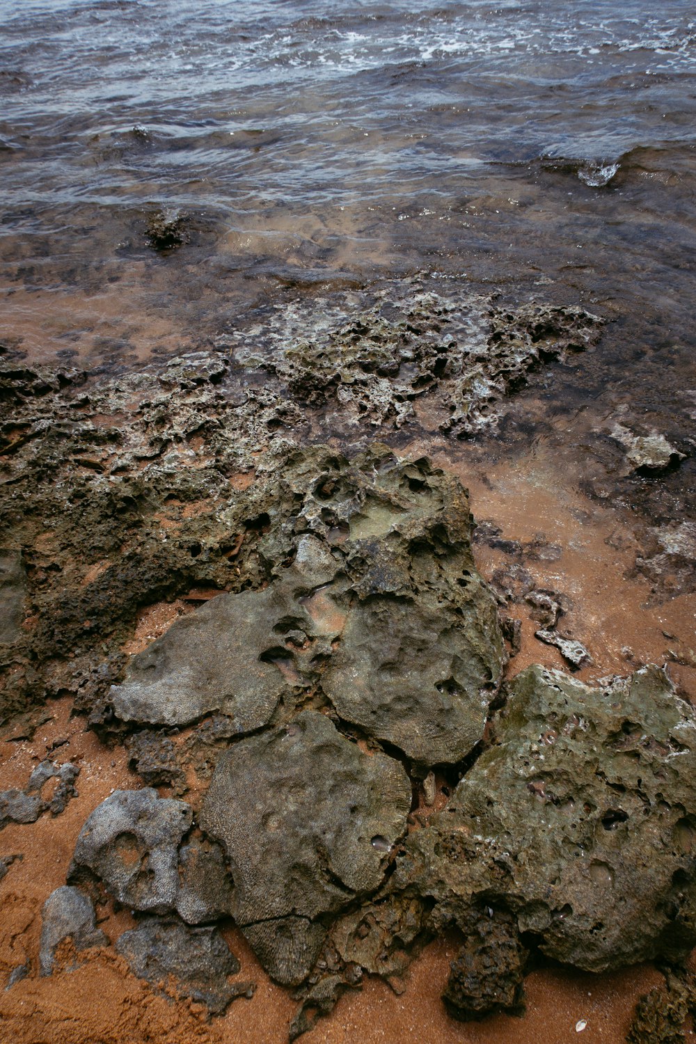 una playa cubierta de rocas con un cuerpo de agua al fondo