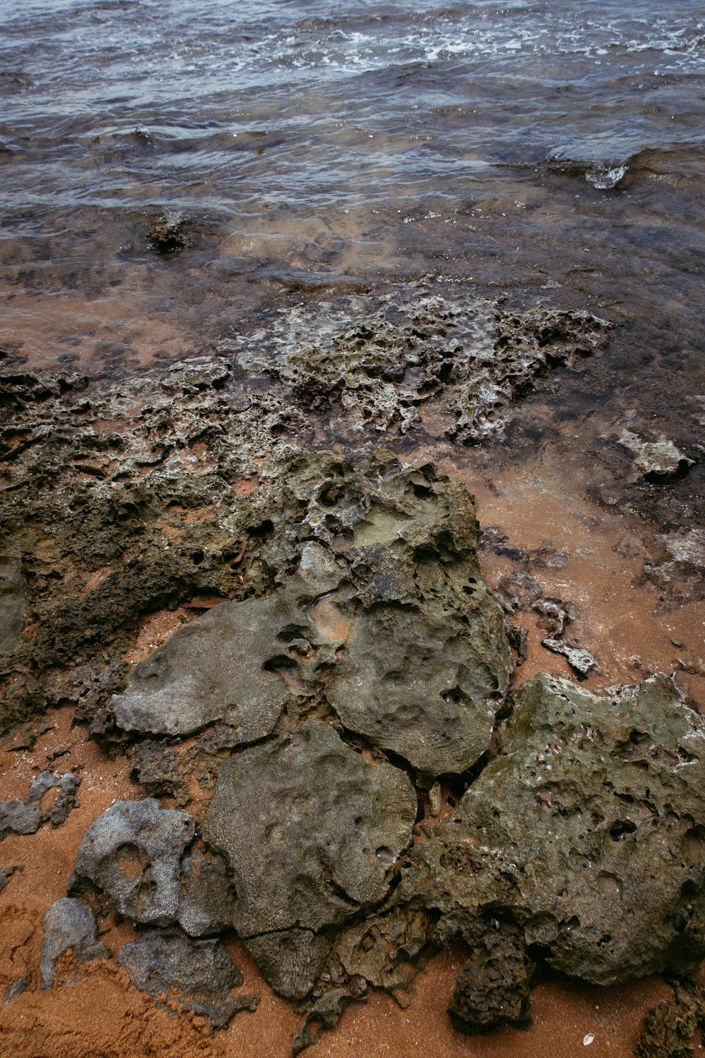 a rock covered beach with a body of water in the background