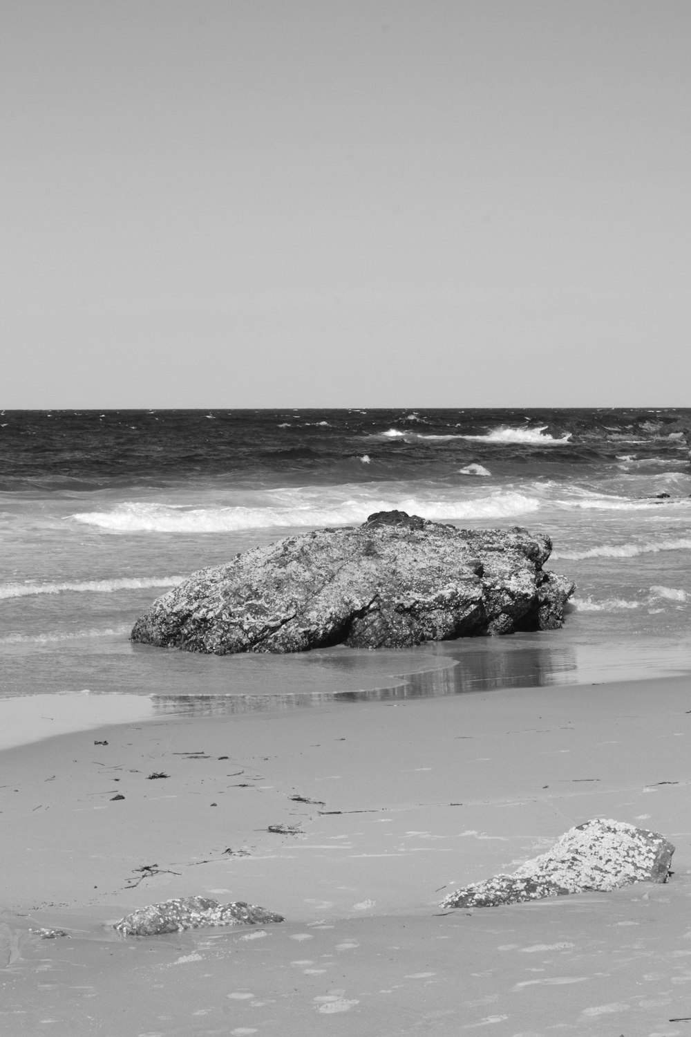 a black and white photo of a rock on the beach