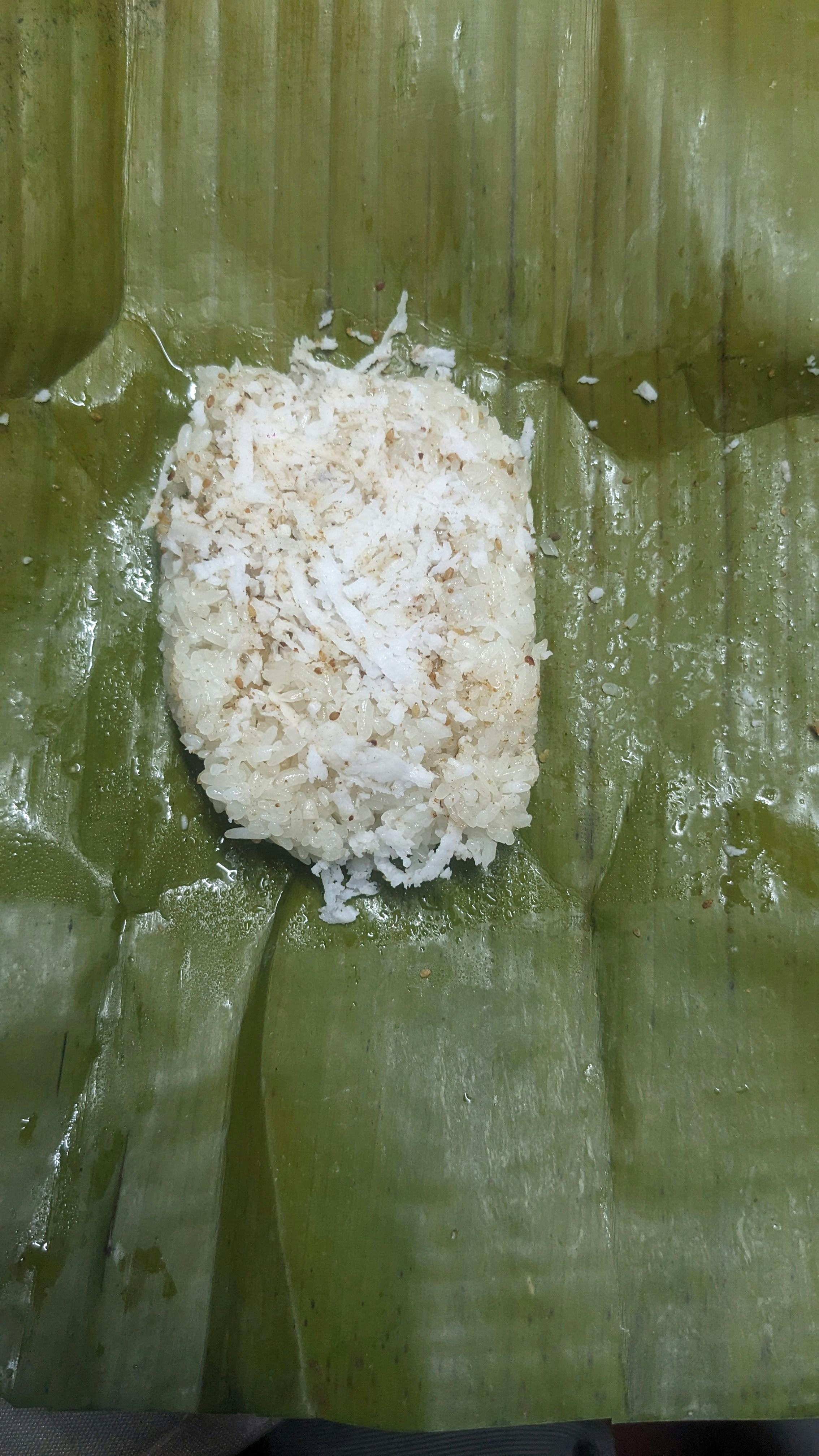 Coconut rice with fish curry in a banana leaf on a wooden table