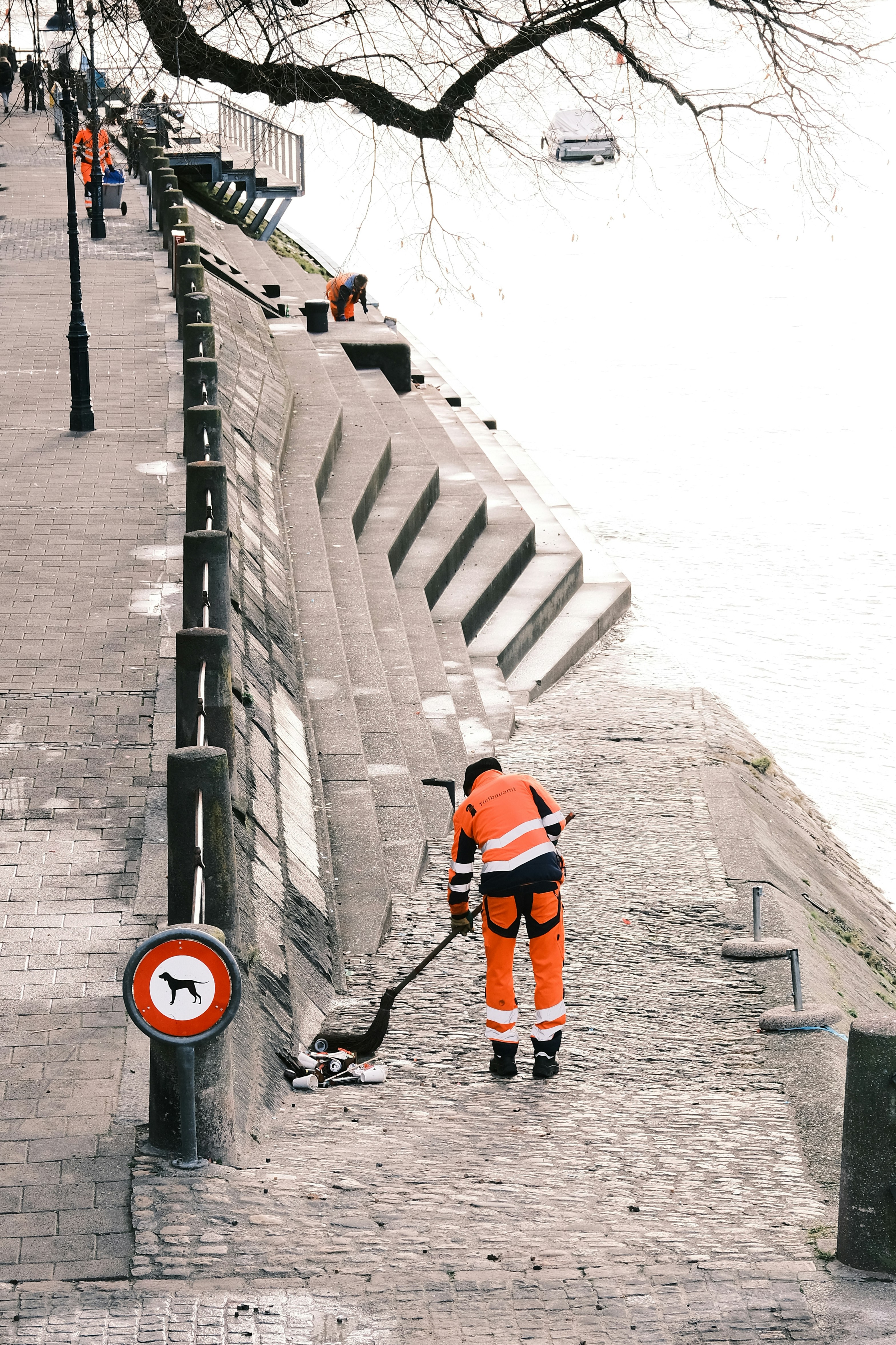a man in an orange safety suit is cleaning a street