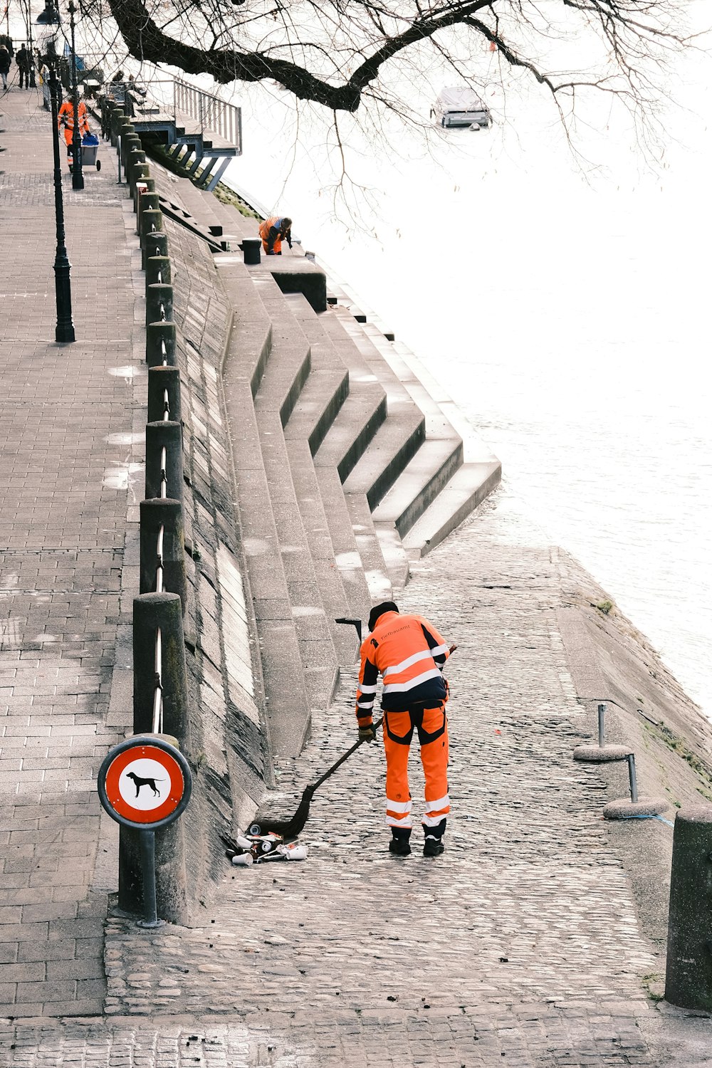 a man in an orange safety suit is cleaning a street