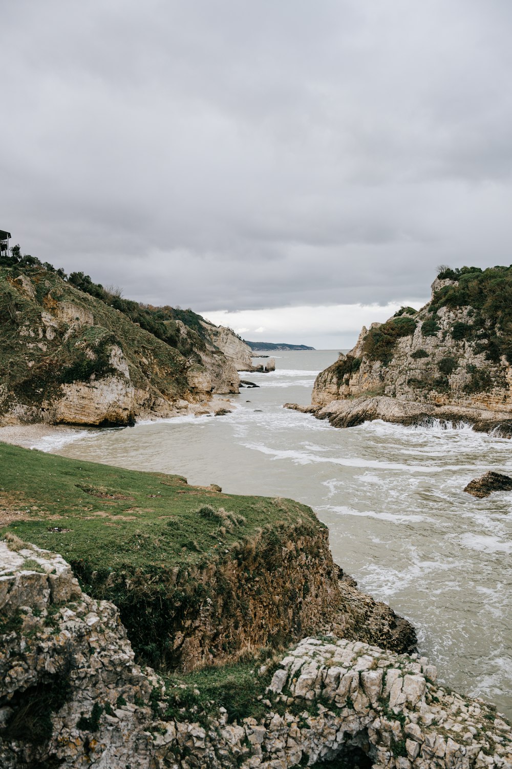 a body of water surrounded by rocks and grass