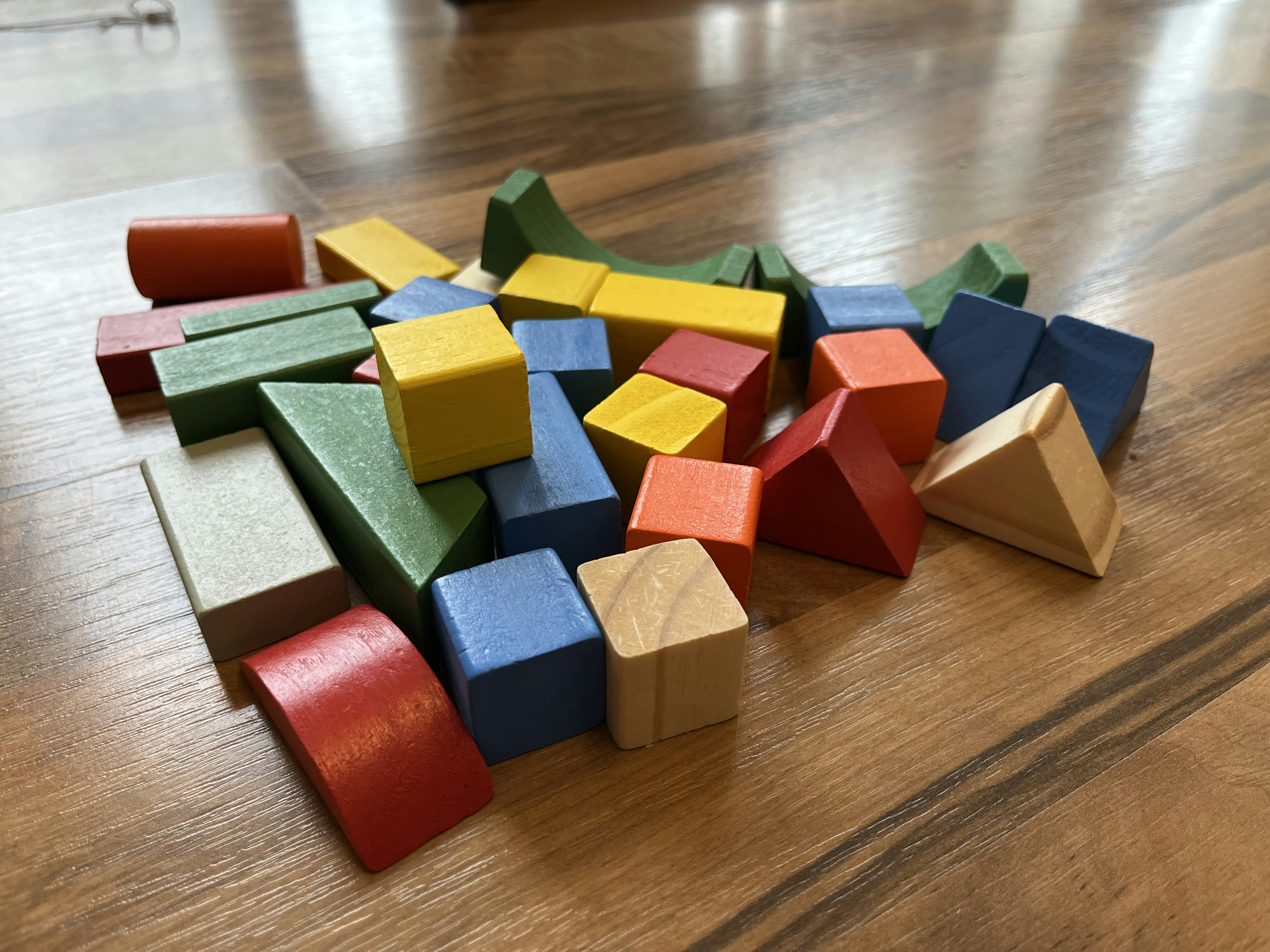 Colorful toy blocks and board games on light wooden floor, bright cheerful lighting