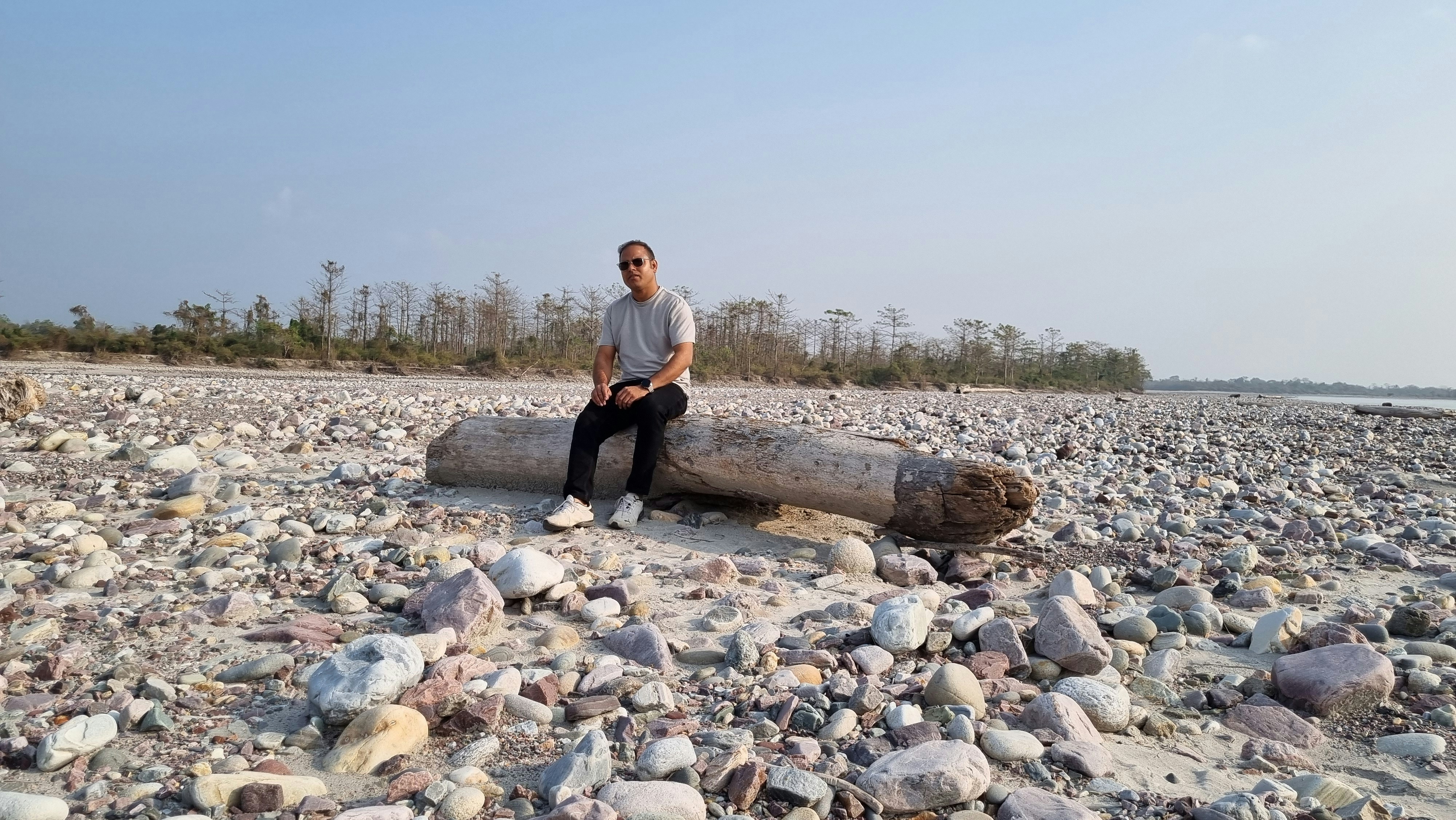 A man sitting on a log on a rocky beach