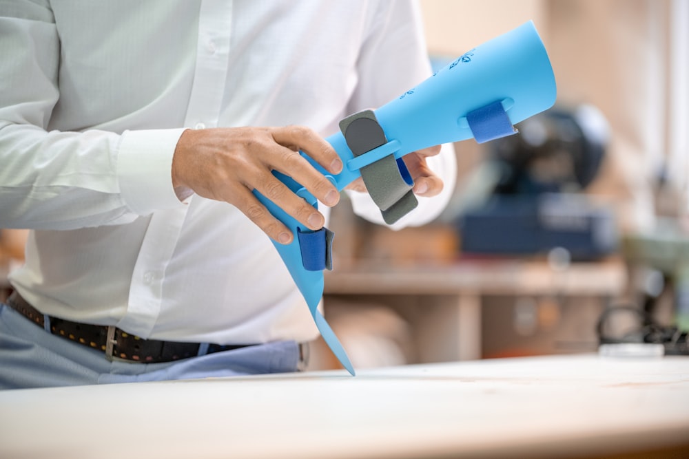 a man holding a blue hair dryer on top of a table