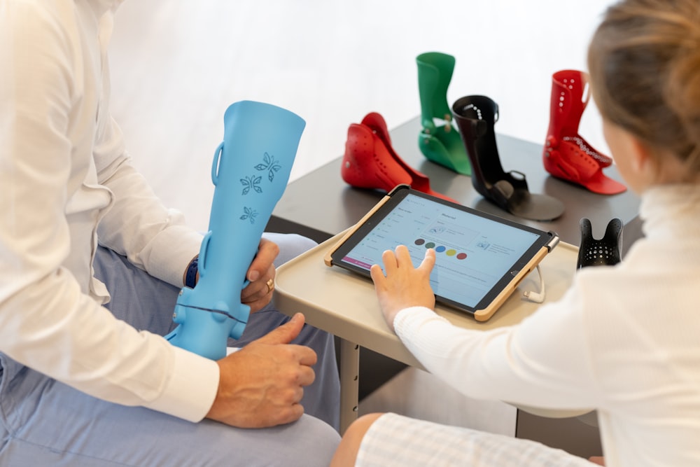 a man and a woman sitting on a table with a tablet