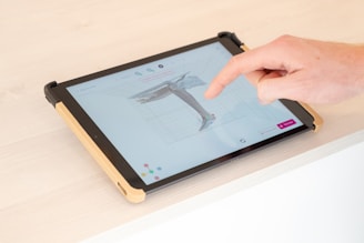 a person is pointing at a tablet screen