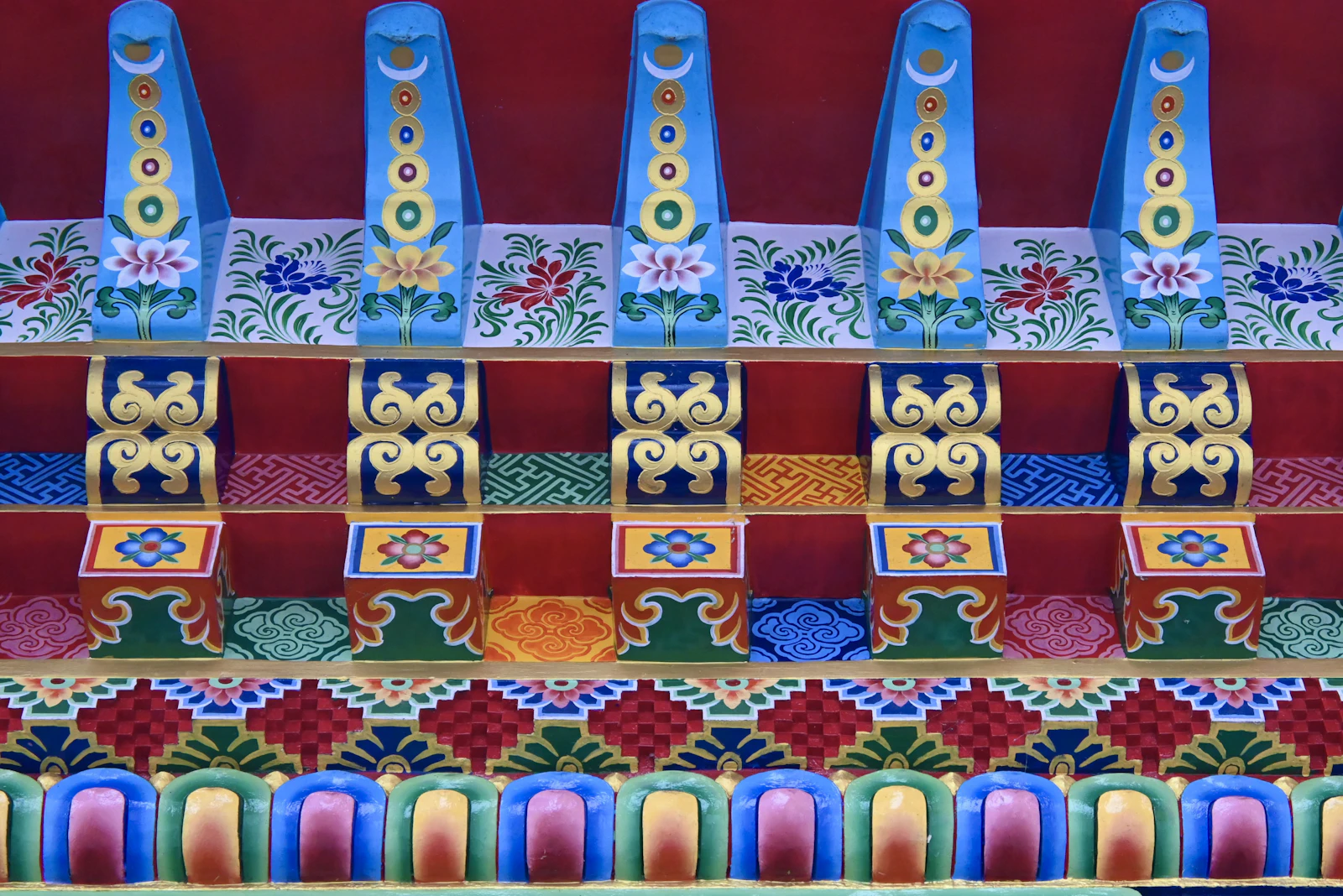 Painted rafter ends and carved brackets in blue, gold and red under the eaves of Enchey Monastery in Gangtok